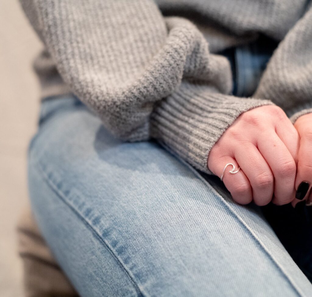 Hands resting on jeans in a grey knit sweater
