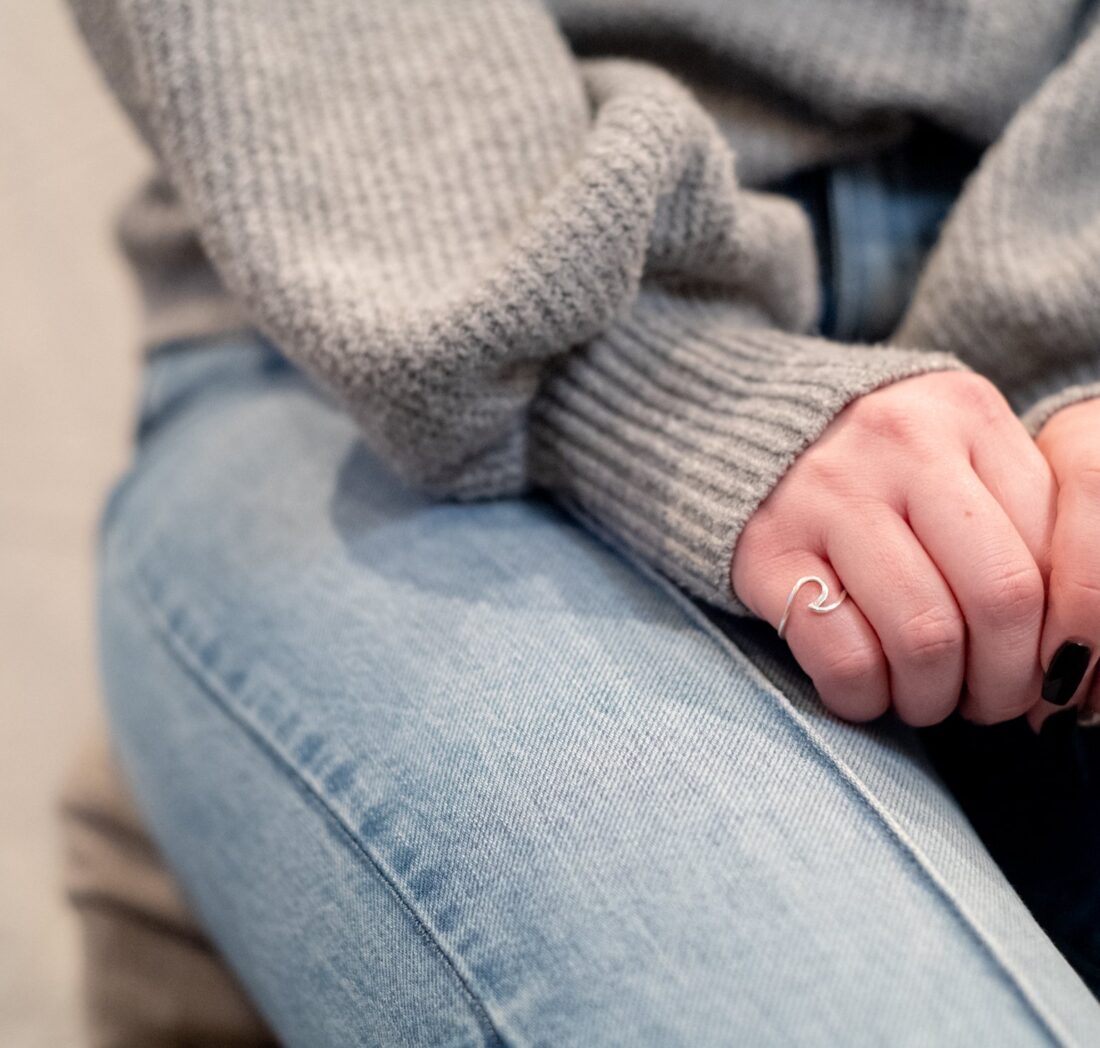 Hands resting on jeans in a grey knit sweater