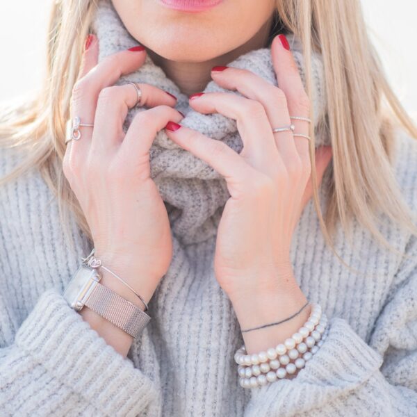 A woman pulling up the neck of a soft grey merino rollneck