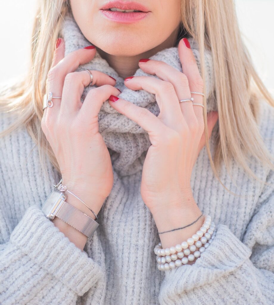 A woman pulling up the neck of a soft grey merino rollneck