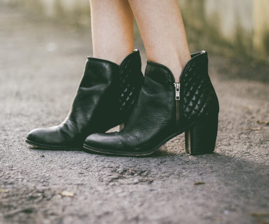 Black quilted ankle boots on a wet pavement