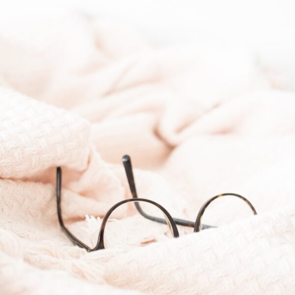 Round wire-frame glasses resting on a soft blush blanket