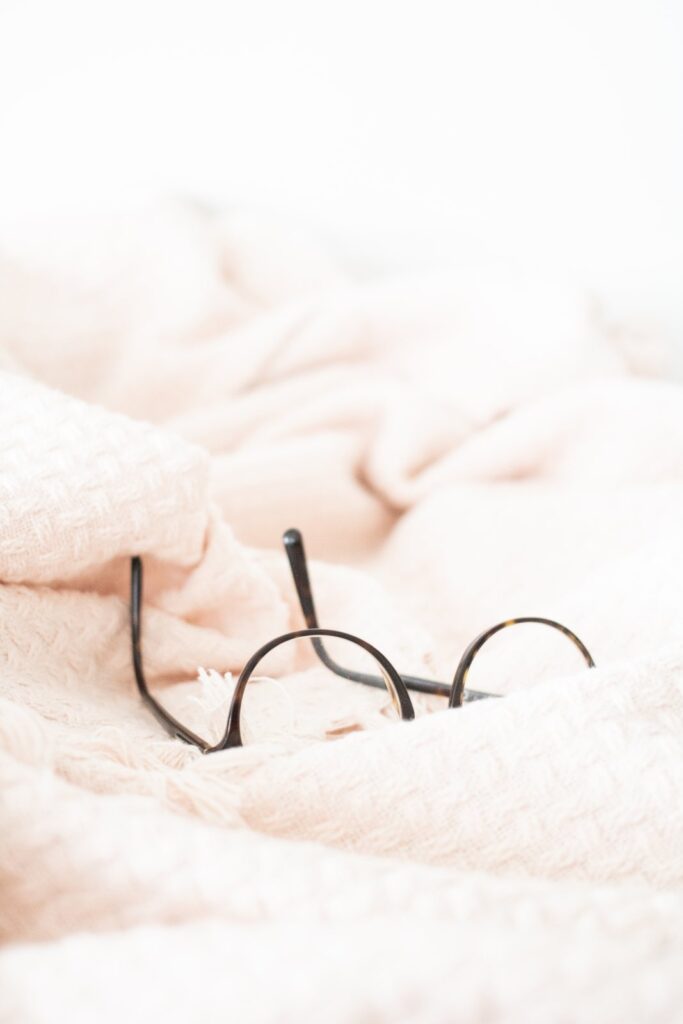 Round wire-frame glasses resting on a soft blush blanket