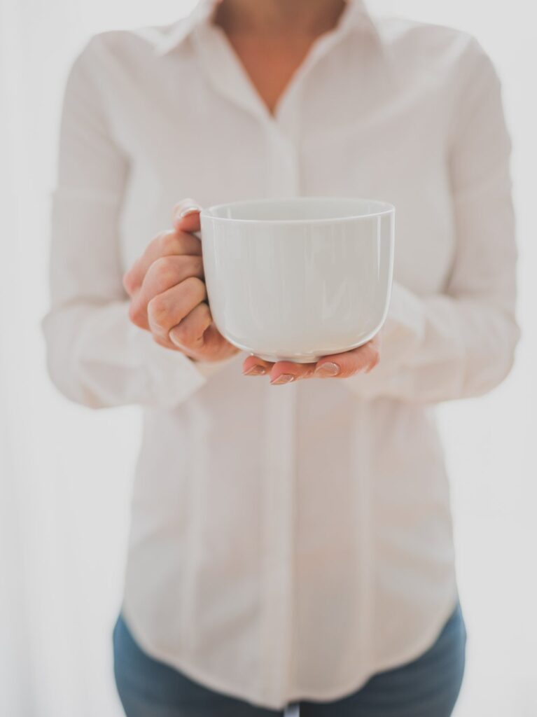 A woman in a white shirt holding a white cup