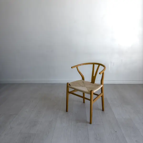 A pale timber chair with a bentwood back, alone against a plain wall