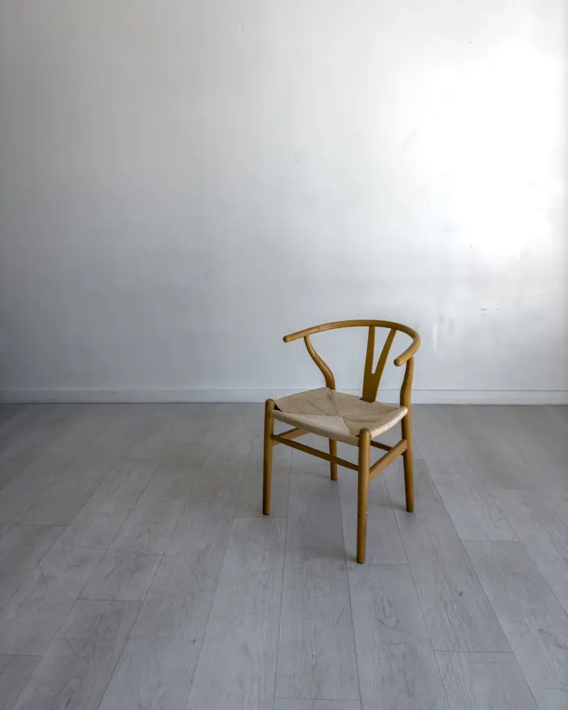 A pale timber chair with a bentwood back, alone against a plain wall