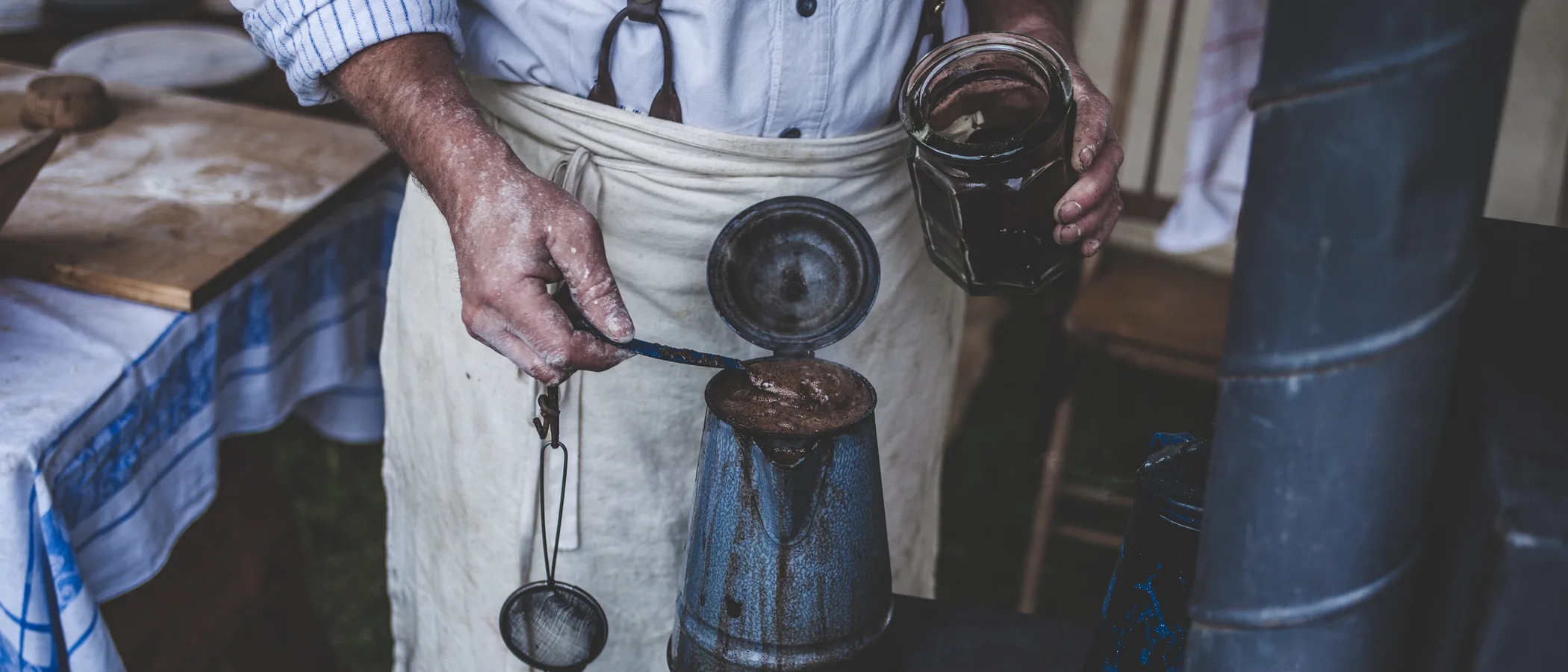 A maker in an apron working at a bench, hands only