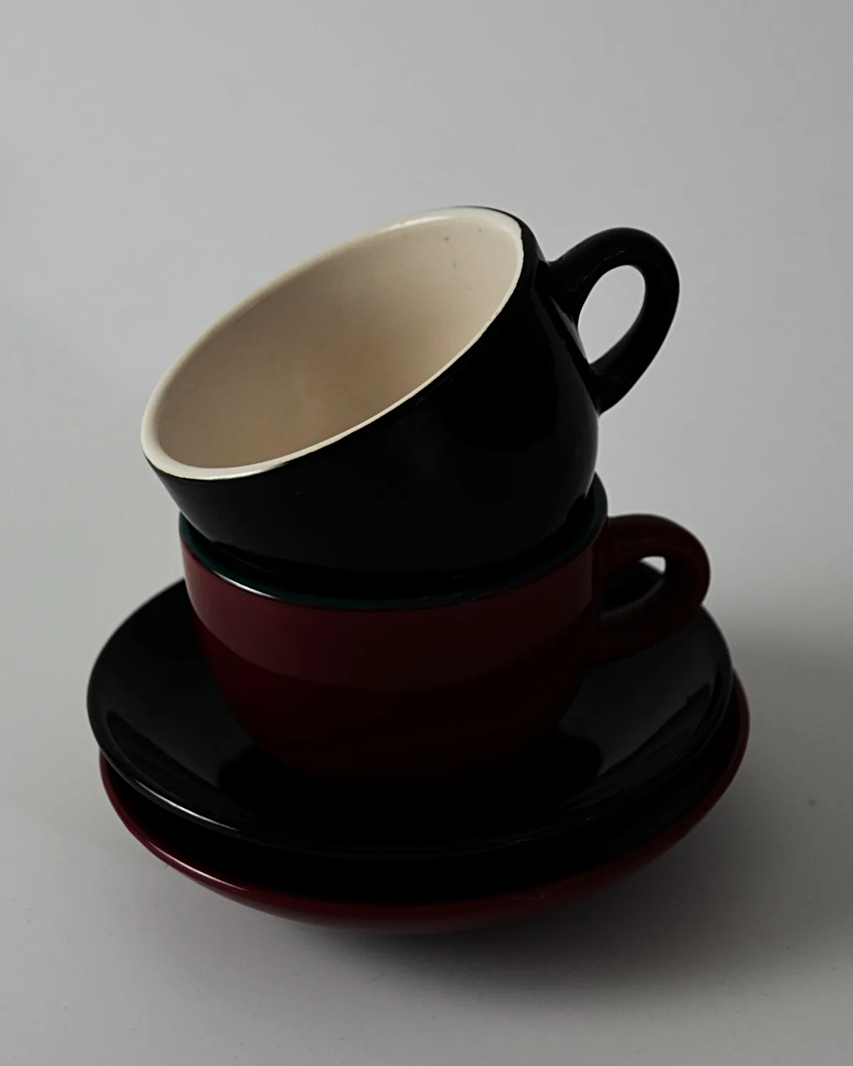 Two stacked cups and saucers in black and deep red