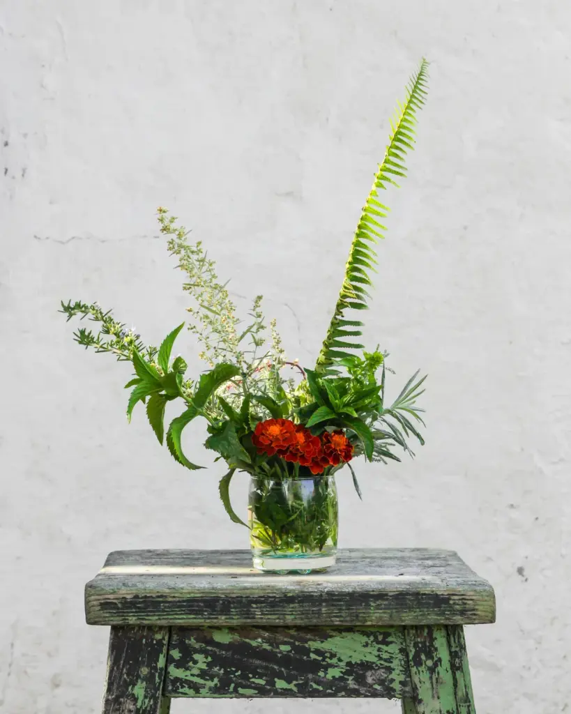 A small green painted stool with a fern on it
