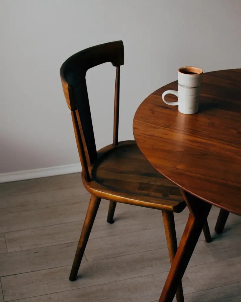 A round walnut table with a chair drawn up to it