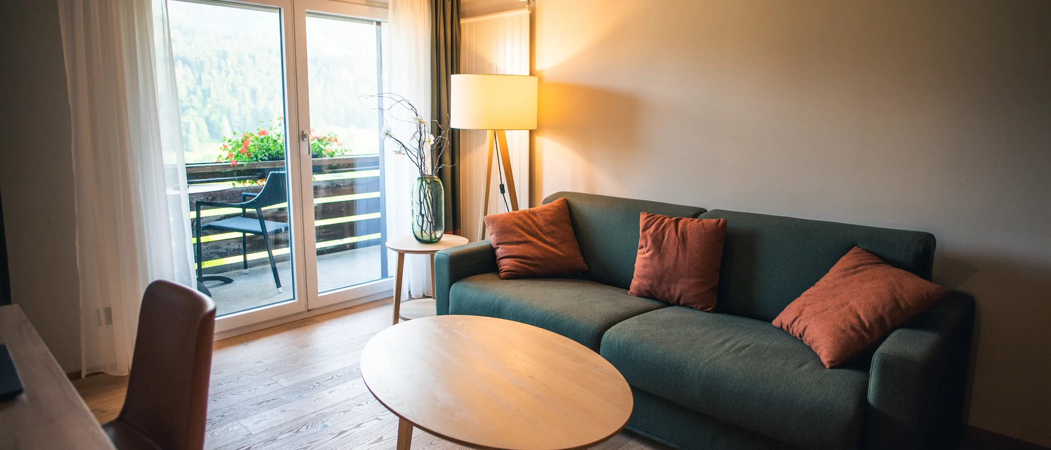 A living room with a green sofa, a round table and a lamp