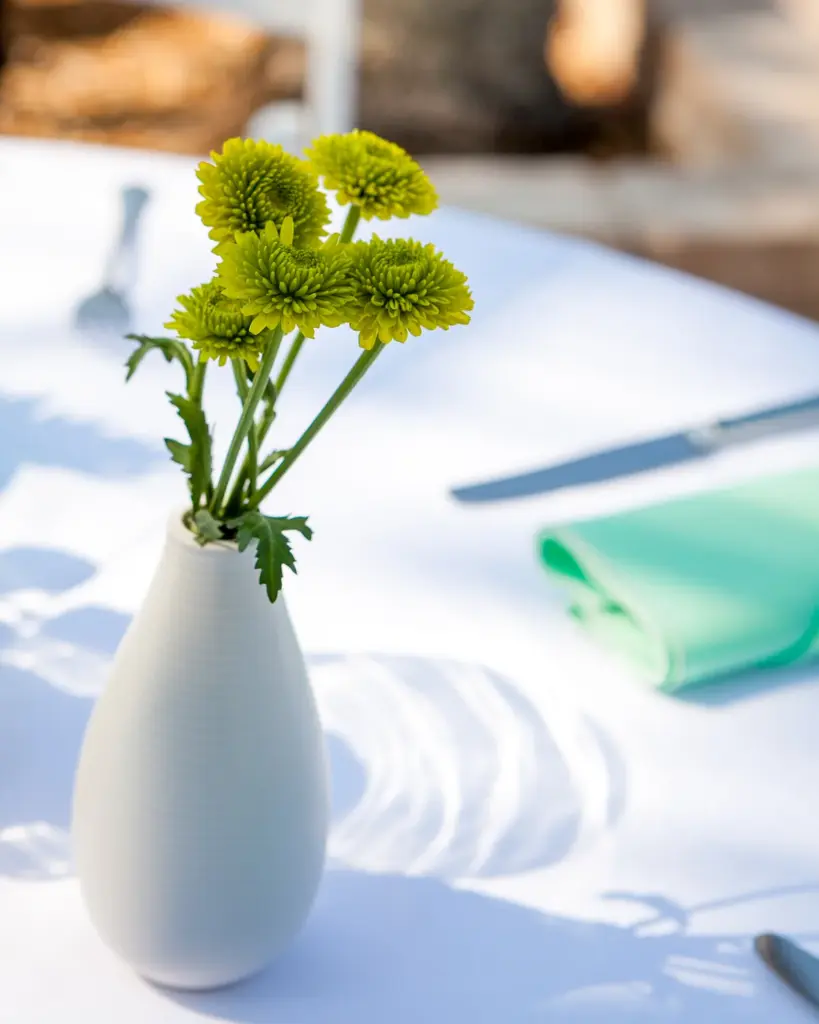A small white vase with a few yellow stems