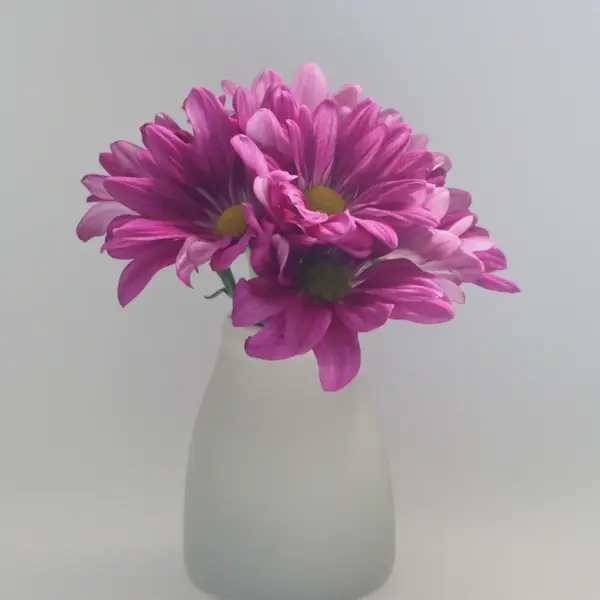 A frosted grey vase holding pink flowers