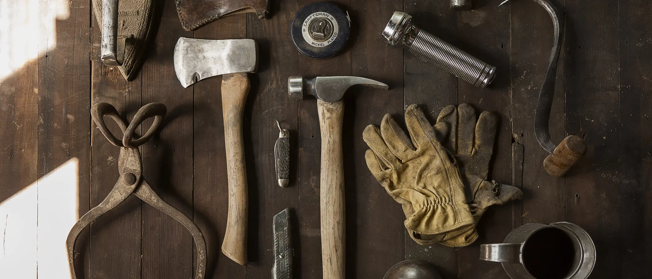 Old hand tools laid out in rows on a dark bench