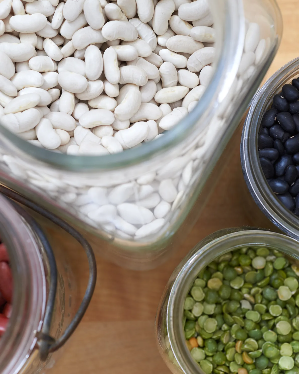 Jars of white, kidney and black beans with bowls