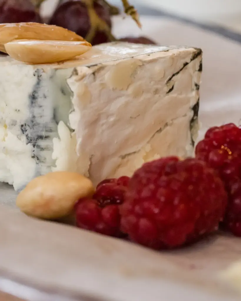 A wedge of blue cheese with raspberries and almonds
