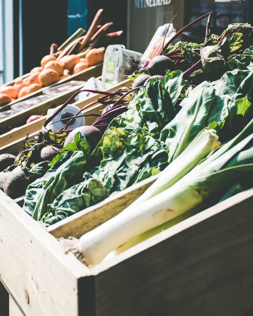 Leeks and greens in a wooden crate at a market