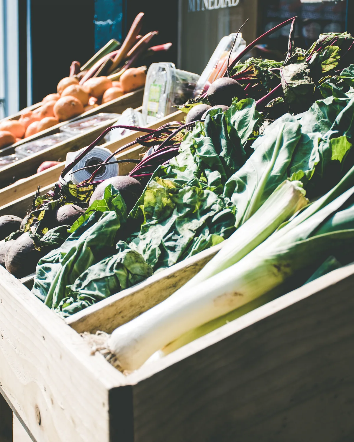 Leeks and greens in a wooden crate at a market