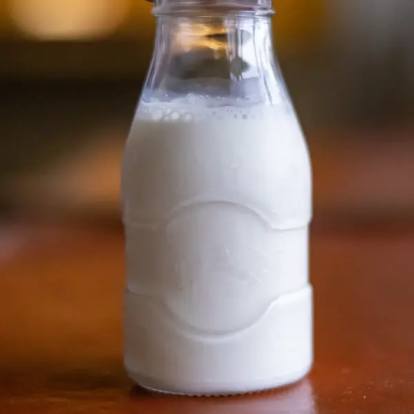 A glass bottle of milk on a dark table