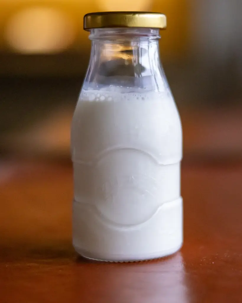 A glass bottle of milk on a dark table
