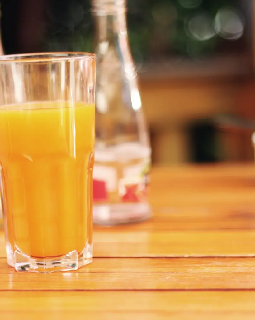 A glass of orange juice on a wooden table