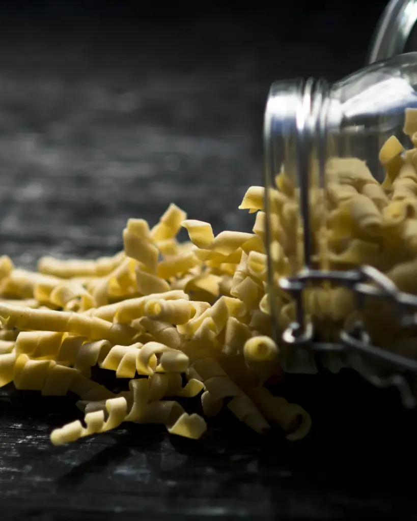 Dried pasta spilling from a glass jar