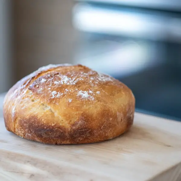A round sourdough loaf on a wooden board