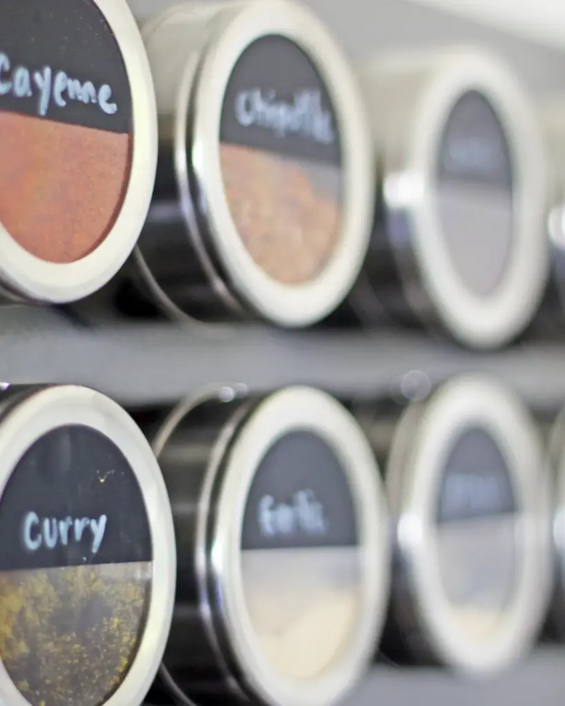 A row of spice tins with handwritten chalk labels