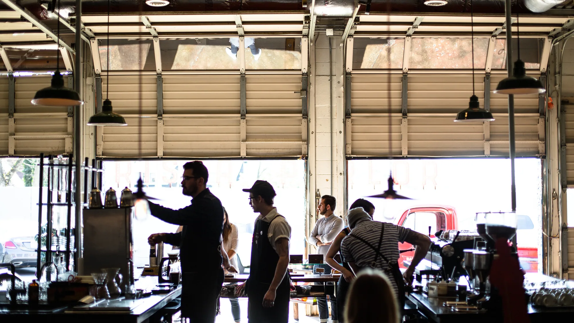 A wide roastery with daylight flooding in through open shutter doors