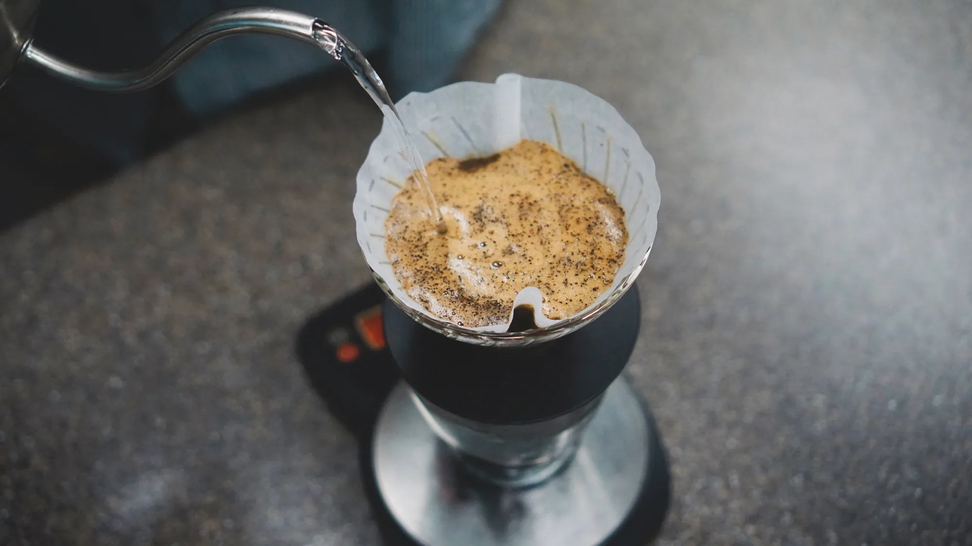 Hot water falling onto a blooming bed of coffee grounds in a white paper filter