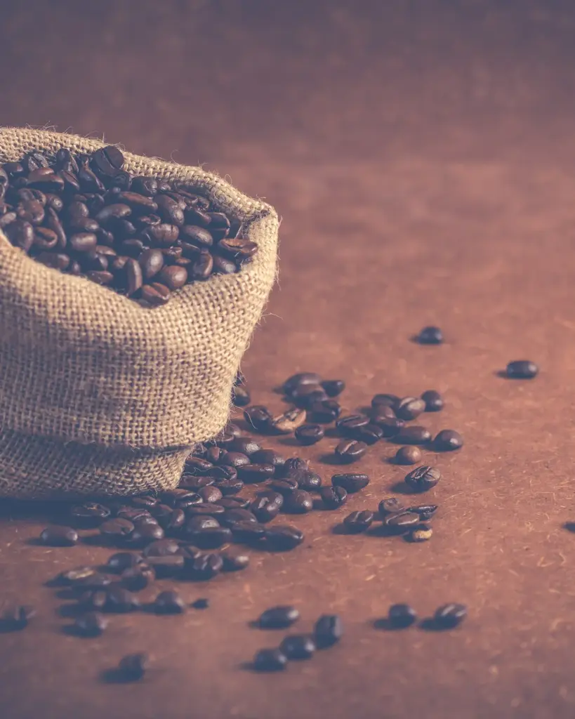 A small open hessian sack spilling over with roasted coffee beans