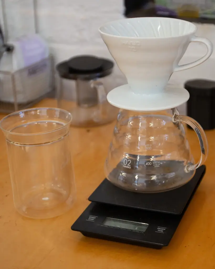 A white ceramic cone on a glass server, standing on a digital brew scale