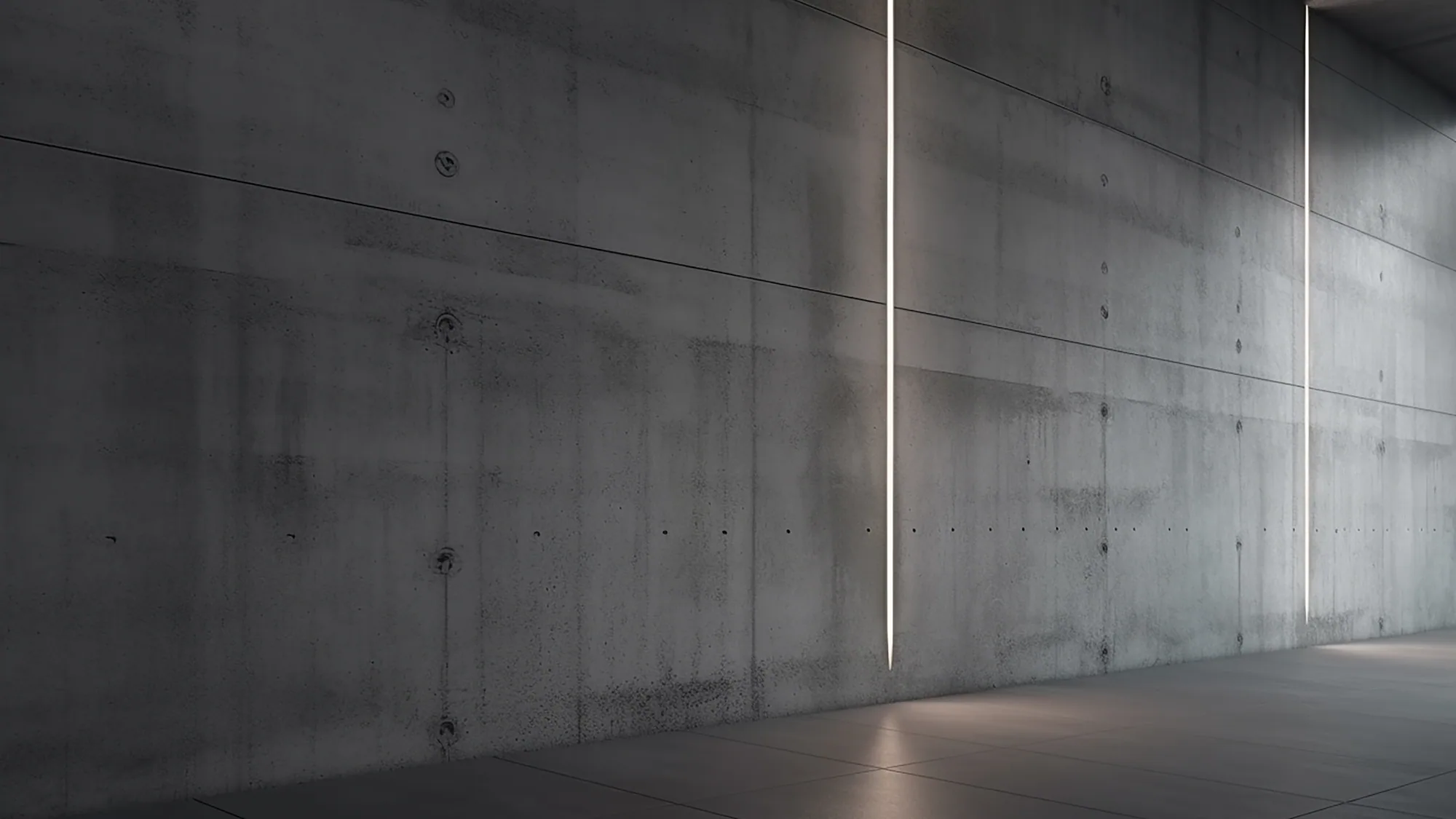A long cast-concrete wall receding into shadow above a polished floor