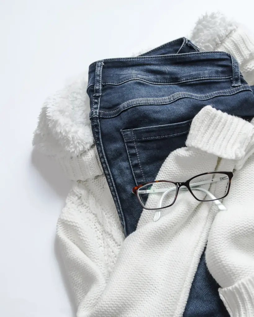 A folded cream cable-knit sweater on a white ground