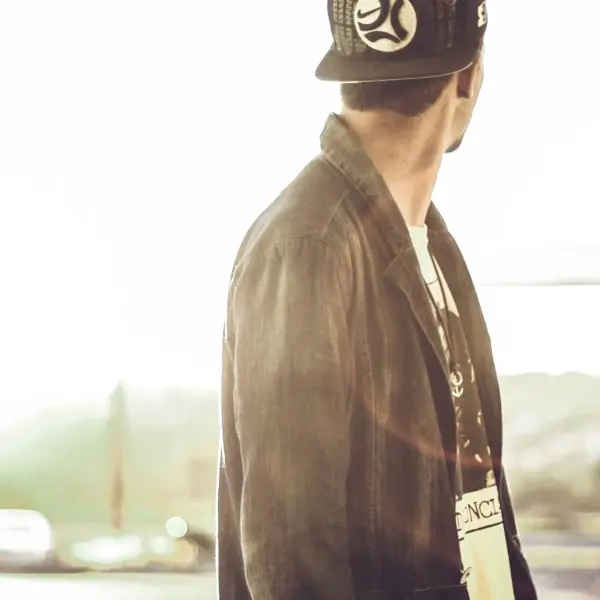 A person in a six-panel cap seen from the side in low sun