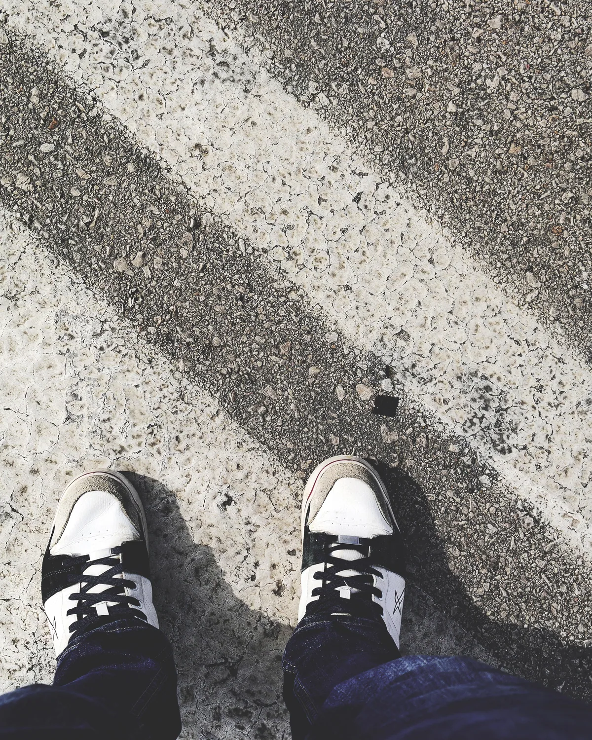 Black skate shoes seen from above on sunlit concrete