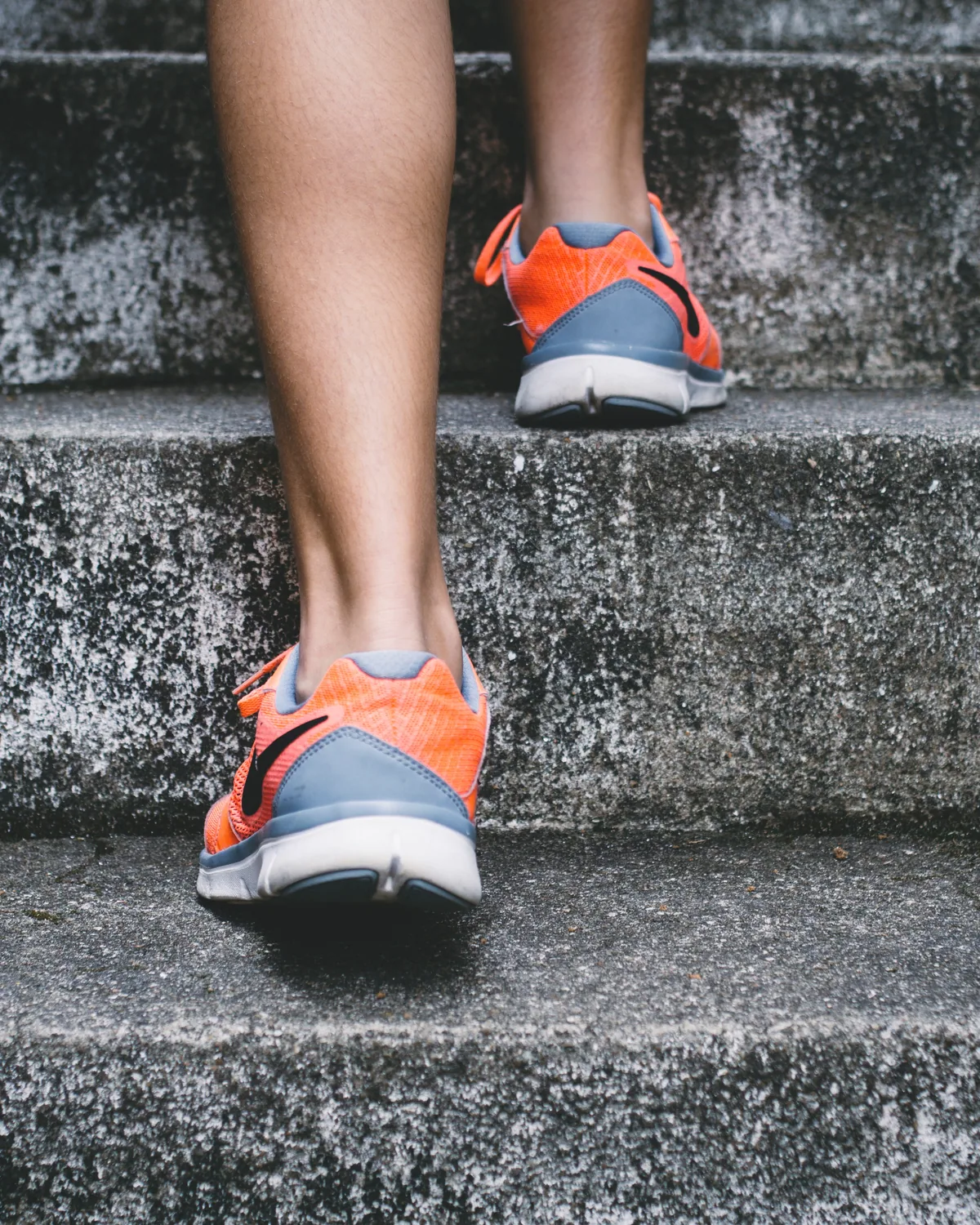 Orange and grey running shoes climbing wet concrete steps