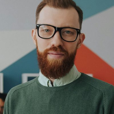Callum Reece, design director at Northbank, in a green jumper in front of the studio mural