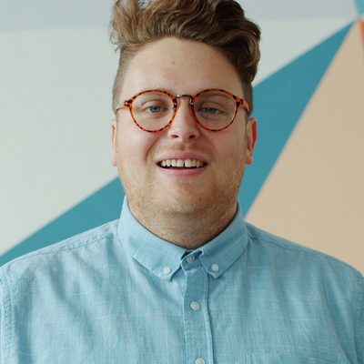 Marek Stolar, engineering lead at Northbank, in a blue shirt and round glasses against the studio's painted wall