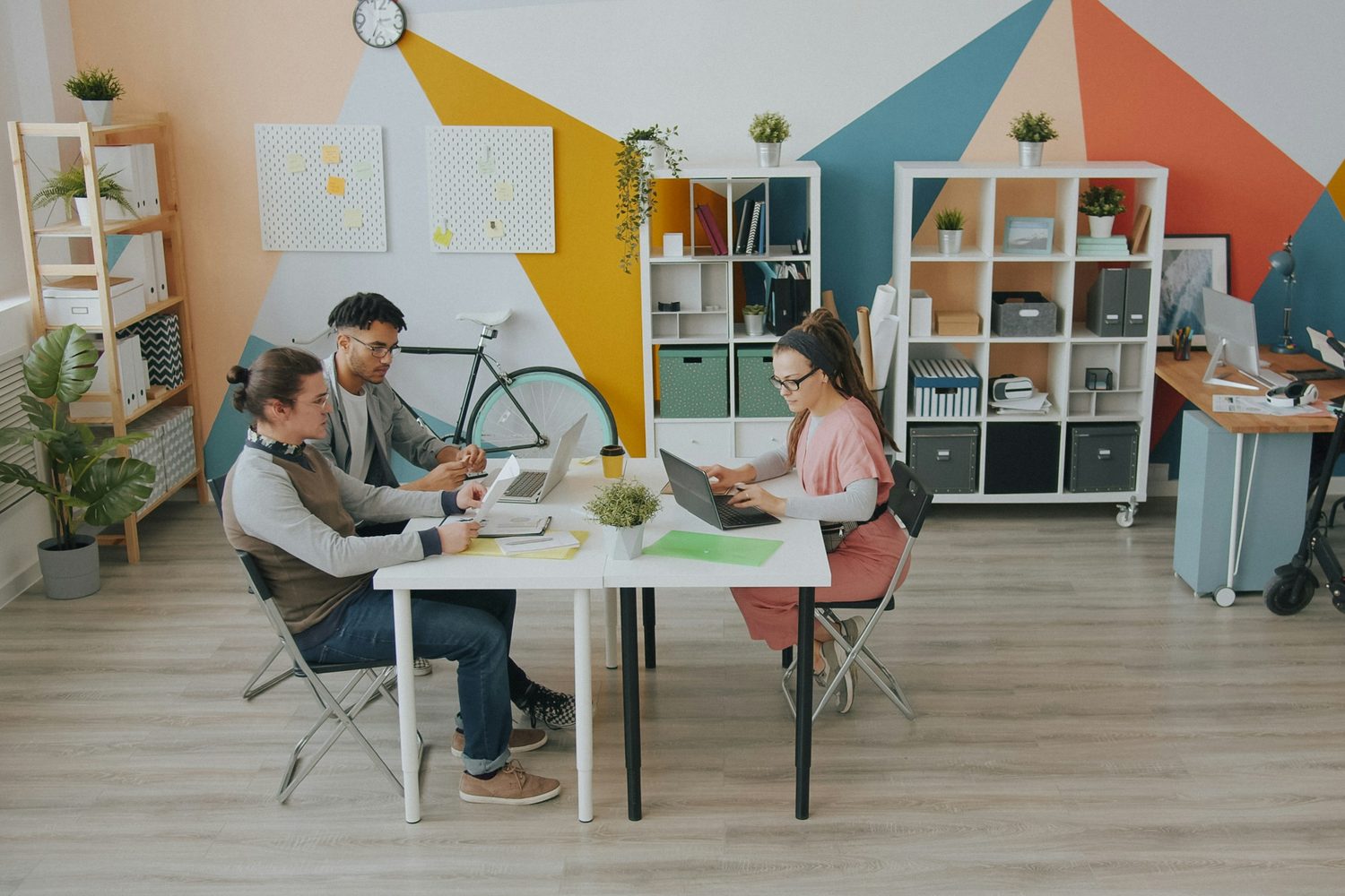 An ordinary working day at Northbank's Manchester studio, two people going through something together at the table while a third works alongside