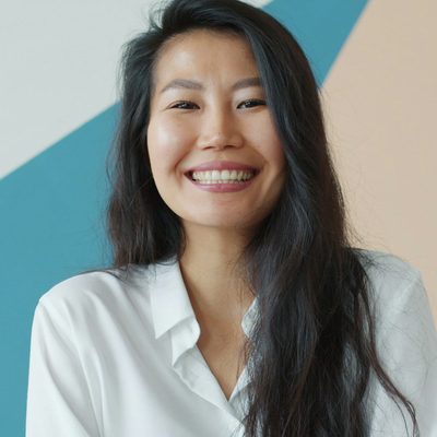 Yumi Adeyemi, product designer at Northbank, smiling in a white shirt against the studio's painted wall