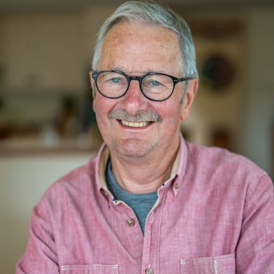 Tom Iredale, lead pastor, a grey-haired man in glasses and a pink shirt smiling warmly