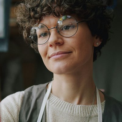 Ivy Sandoval, letterpress and bookbinding tutor, in round glasses and a work apron in her studio