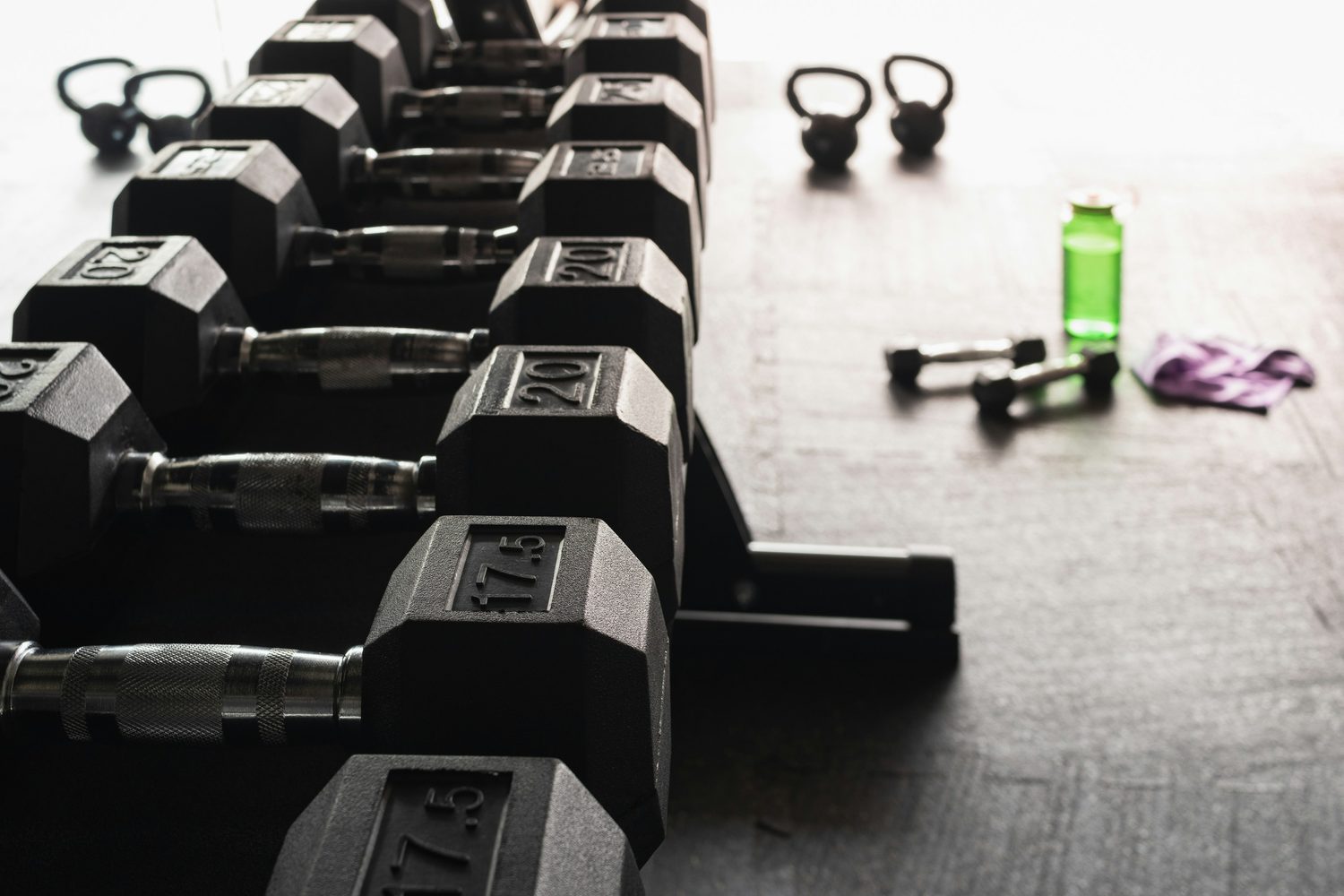 The dumbbell rack at Ironworks with a light pair and a resistance band left out on the floor beside it