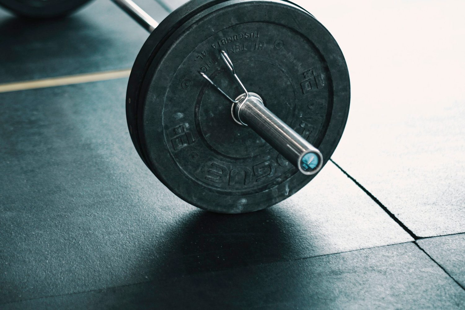A barbell still loaded, resting on the floor of the Ironworks training room in the light from the windows