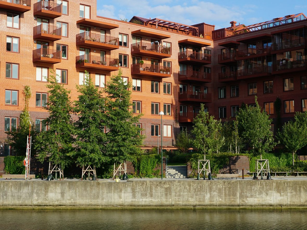 Meridian Housing homes: red-brick apartment blocks with balconies along a tree-lined waterfront