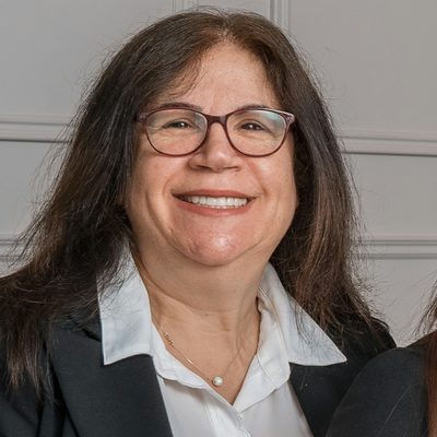 Dr Anna Petrou, principal dentist at Fore Street Dental, smiling in glasses