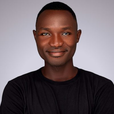 Dr Samuel Oyelaran, implant and restorative dentist at Fore Street Dental, smiling against a grey wall