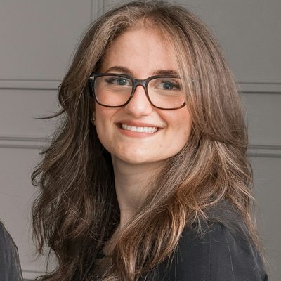 Marie Colbert, dental hygienist at Fore Street Dental, smiling in glasses and dark scrubs