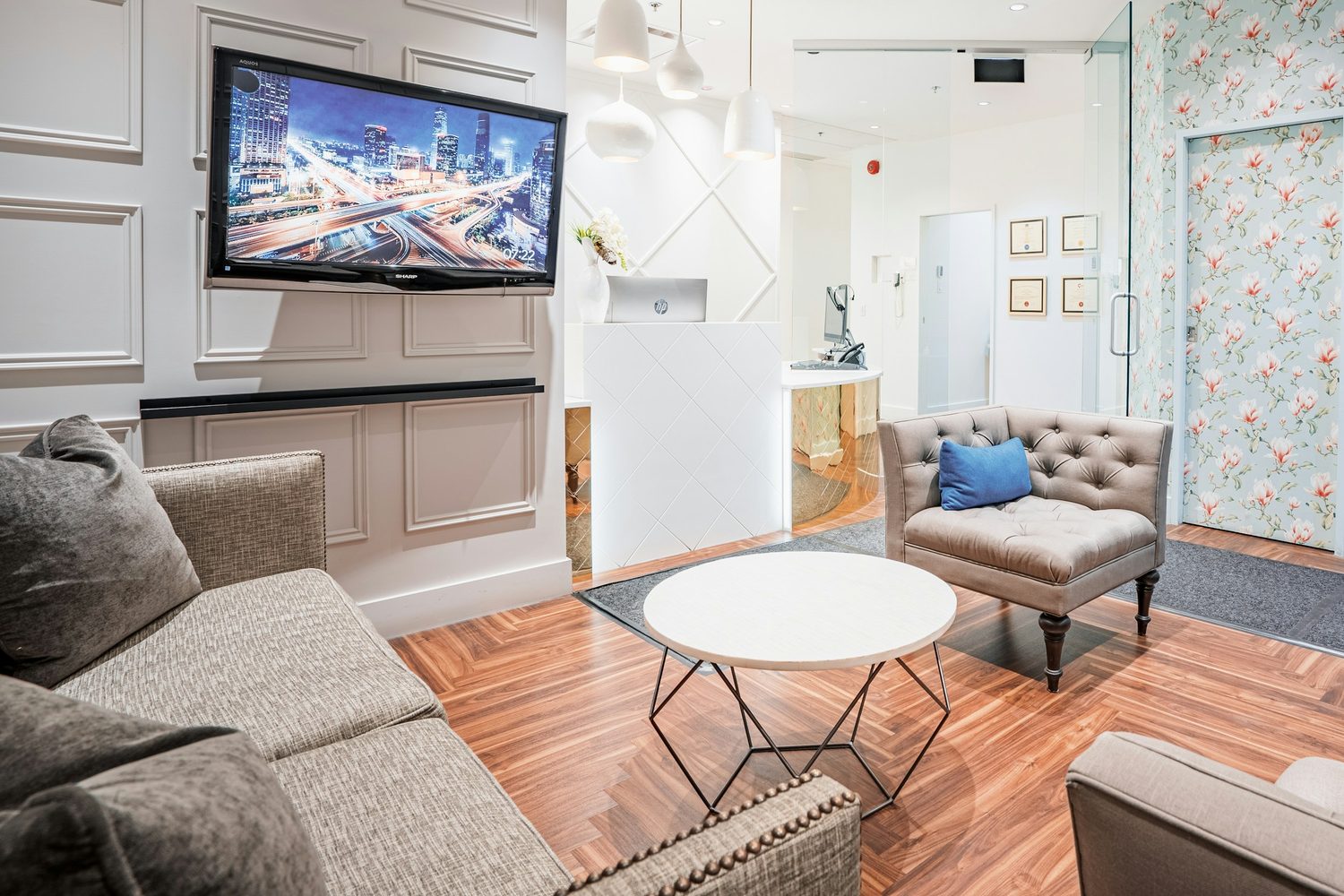 The bright waiting room at Fore Street Dental, with sofas, a round table and the reception desk just beyond